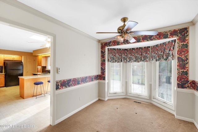 dining room with visible vents, light colored carpet, wainscoting, and crown molding