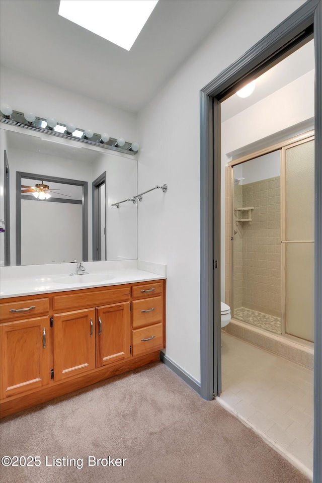 bathroom with toilet, a stall shower, carpet floors, a skylight, and vanity