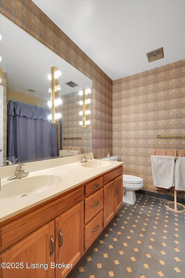 full bath featuring visible vents, wallpapered walls, and a sink