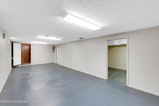 finished below grade area featuring visible vents, a textured ceiling, and baseboards