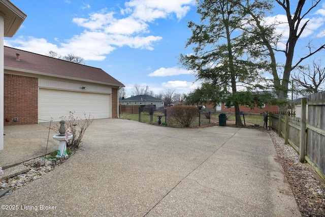 garage with concrete driveway and fence