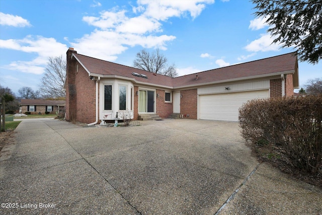 view of front of home with entry steps, concrete driveway, an attached garage, brick siding, and a chimney