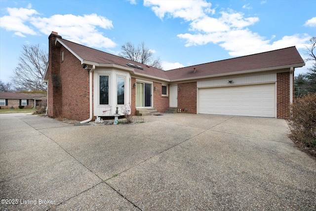 view of front of house featuring driveway, a chimney, entry steps, a garage, and brick siding