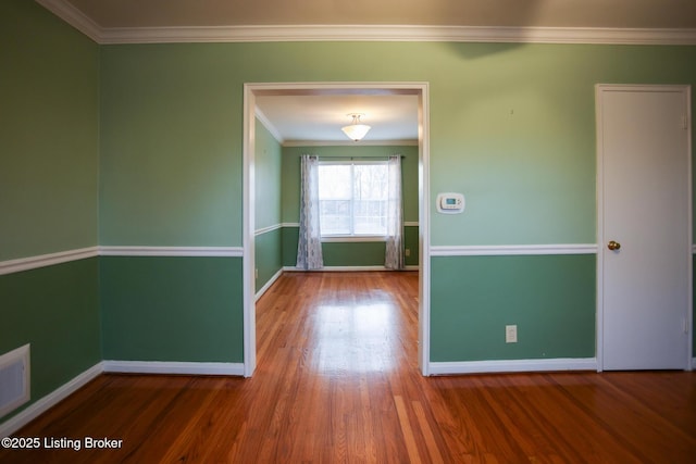 spare room featuring wood-type flooring and ornamental molding