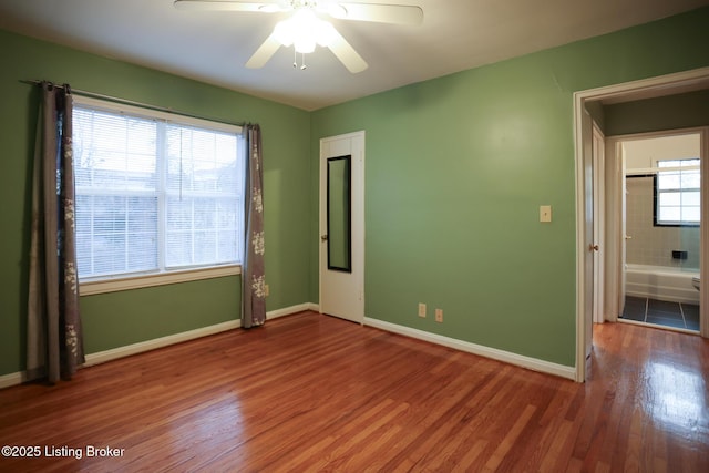 empty room featuring ceiling fan, plenty of natural light, and wood-type flooring