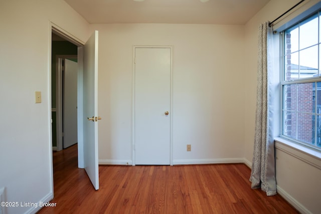 unfurnished bedroom with multiple windows and wood-type flooring