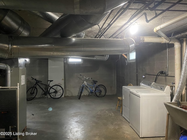 basement featuring sink, independent washer and dryer, and heating unit