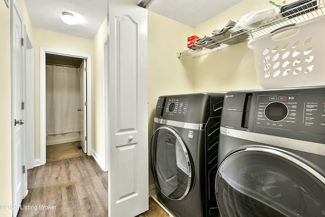 clothes washing area featuring independent washer and dryer, a textured ceiling, and hardwood / wood-style floors