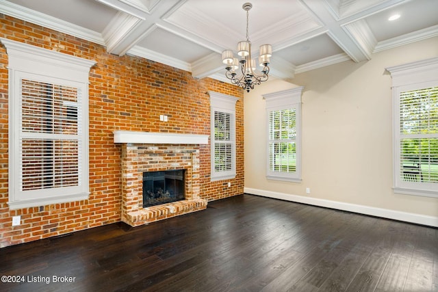 unfurnished living room featuring an inviting chandelier, coffered ceiling, a brick fireplace, beamed ceiling, and brick wall