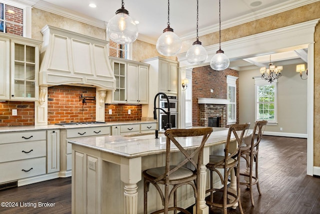 kitchen with an island with sink, hanging light fixtures, and custom range hood