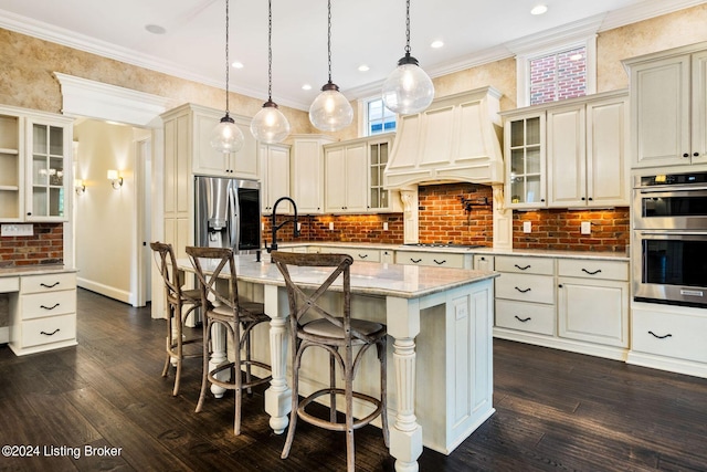 kitchen with premium range hood, a kitchen island with sink, decorative light fixtures, a breakfast bar area, and stainless steel appliances