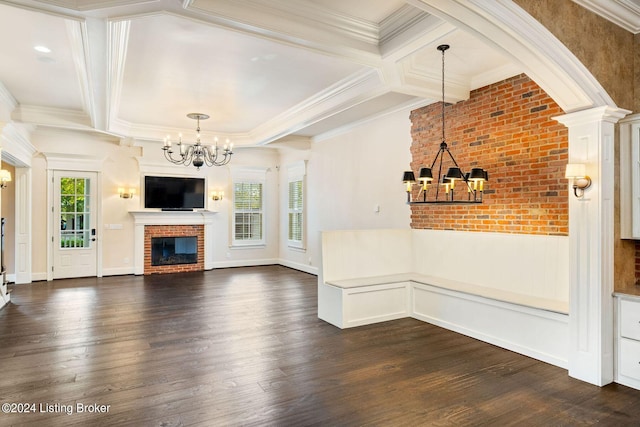 unfurnished living room with crown molding, a chandelier, dark hardwood / wood-style floors, and a brick fireplace