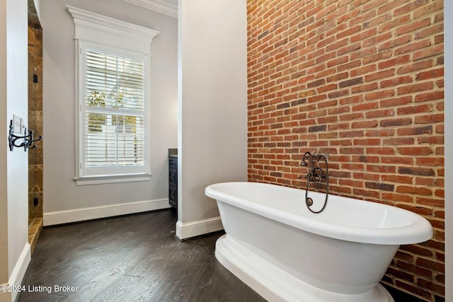 bathroom featuring a tub to relax in, a wealth of natural light, wood-type flooring, and ornamental molding