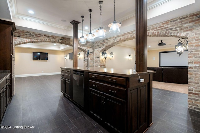 kitchen with pendant lighting, ornamental molding, a kitchen island, dark brown cabinetry, and brick wall