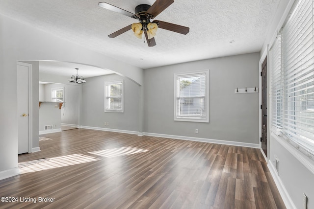 unfurnished living room with ceiling fan with notable chandelier, dark hardwood / wood-style flooring, and a textured ceiling