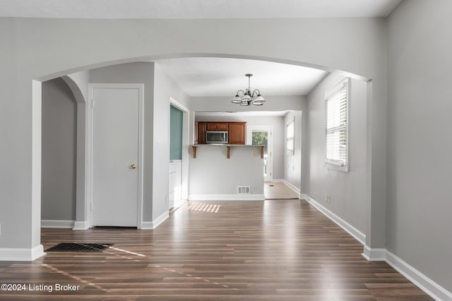 unfurnished living room featuring a notable chandelier and dark wood-type flooring