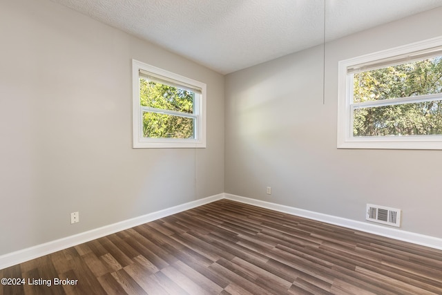 spare room featuring dark hardwood / wood-style flooring and a textured ceiling