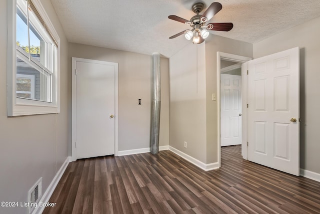 unfurnished bedroom with a textured ceiling, dark hardwood / wood-style flooring, and ceiling fan