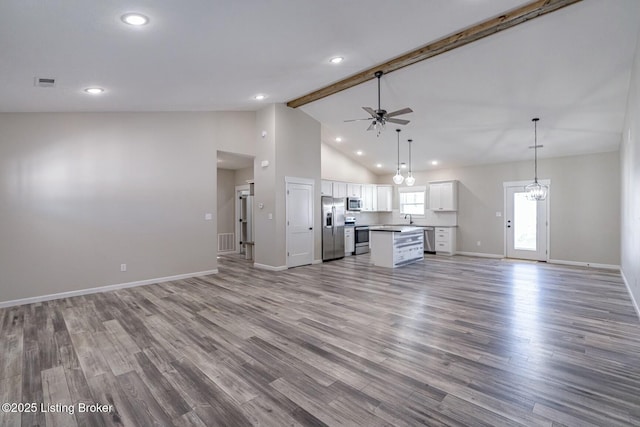 unfurnished living room featuring ceiling fan with notable chandelier, high vaulted ceiling, beam ceiling, light hardwood / wood-style flooring, and sink