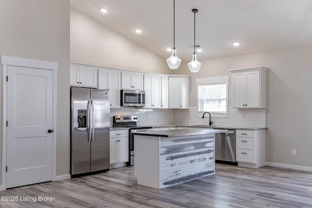 kitchen featuring stainless steel appliances, a center island, pendant lighting, white cabinetry, and backsplash