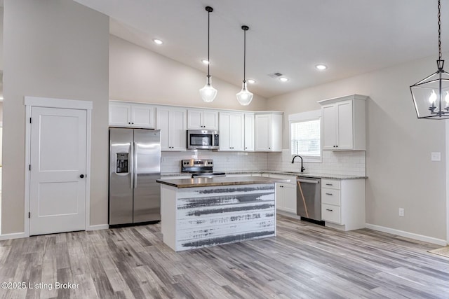 kitchen featuring white cabinetry, a center island, backsplash, pendant lighting, and appliances with stainless steel finishes