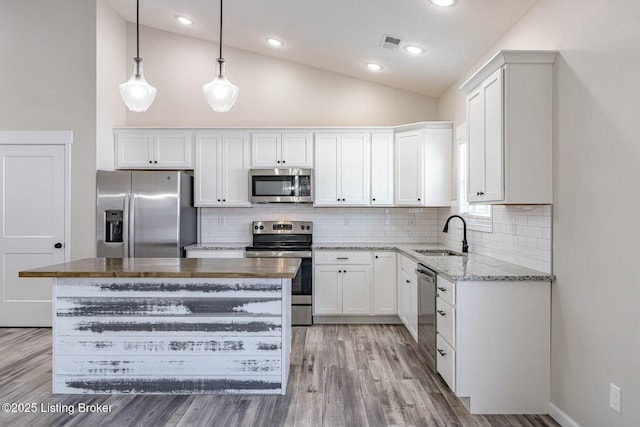 kitchen featuring a center island, hanging light fixtures, stainless steel appliances, white cabinetry, and sink