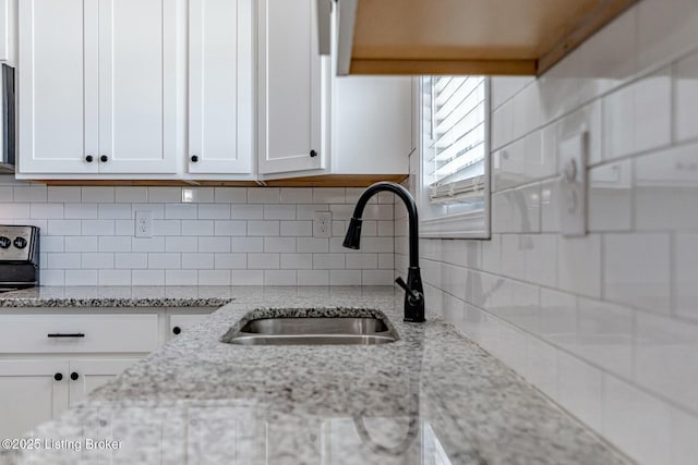 kitchen with decorative backsplash, white cabinetry, and light stone countertops