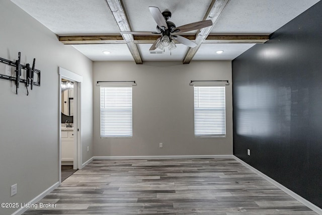 unfurnished room featuring coffered ceiling, hardwood / wood-style floors, ceiling fan, and beamed ceiling