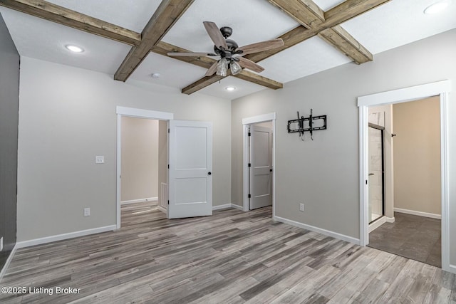 unfurnished bedroom with coffered ceiling, connected bathroom, light wood-type flooring, ceiling fan, and beam ceiling