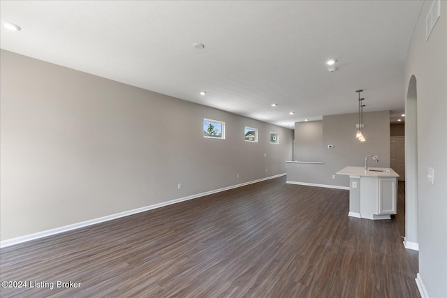 unfurnished living room featuring dark wood-type flooring and sink