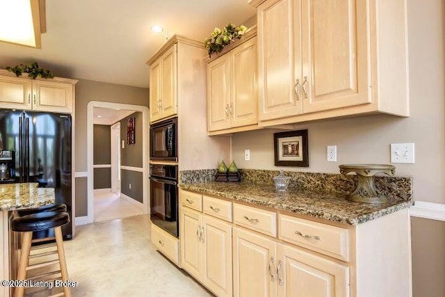 kitchen with dark stone counters and black appliances