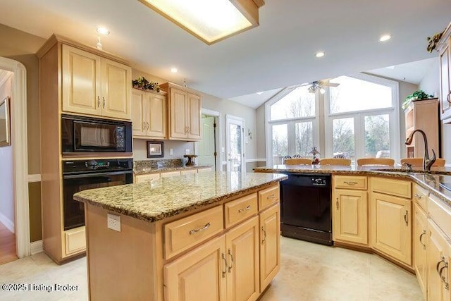 kitchen featuring vaulted ceiling, ceiling fan, sink, black appliances, and a center island with sink