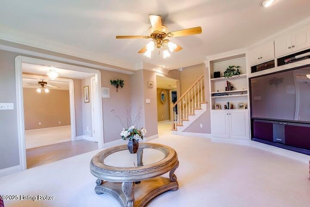 living room featuring built in shelves, ceiling fan, and ornamental molding