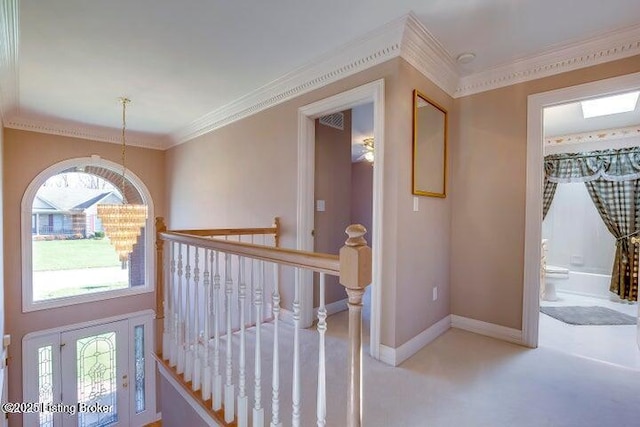 hall featuring light carpet, plenty of natural light, crown molding, and an inviting chandelier