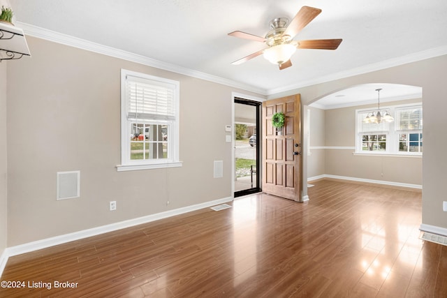 spare room featuring hardwood / wood-style floors, ceiling fan with notable chandelier, and crown molding