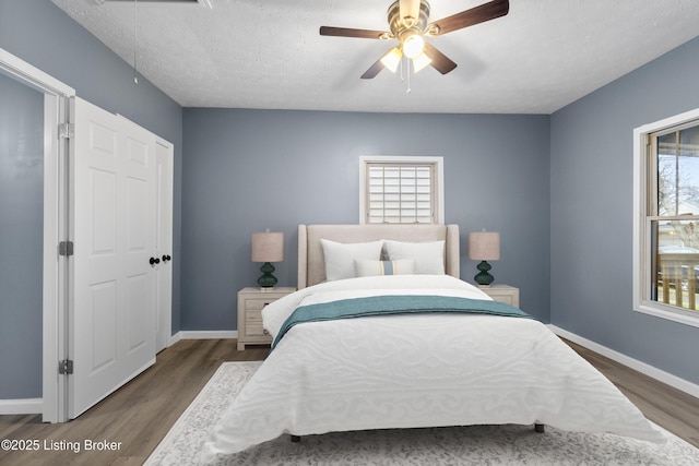 bedroom featuring multiple windows, a textured ceiling, dark hardwood / wood-style floors, and ceiling fan