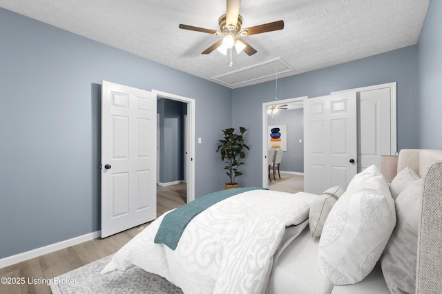 bedroom featuring ceiling fan, light hardwood / wood-style floors, and a textured ceiling