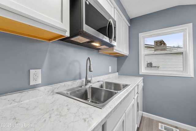 kitchen featuring white cabinetry, sink, dishwasher, and hardwood / wood-style flooring