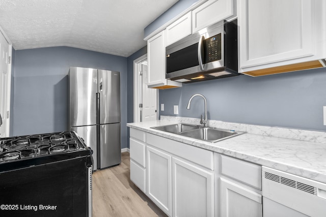 kitchen featuring a textured ceiling, stainless steel appliances, white cabinetry, and sink