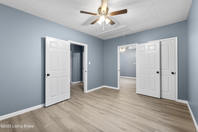 unfurnished bedroom with ceiling fan, a textured ceiling, and light wood-type flooring