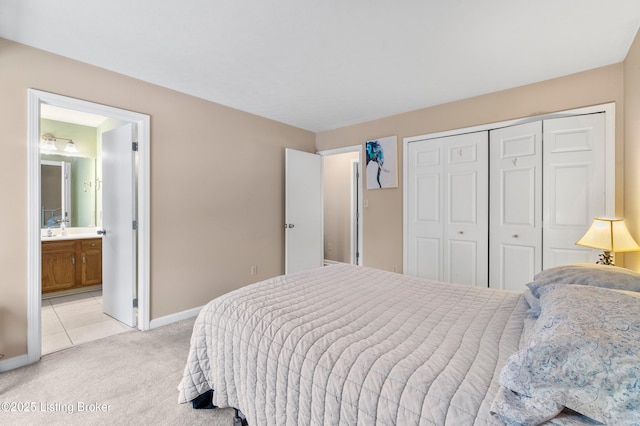 bedroom featuring sink, ensuite bath, a closet, and light colored carpet