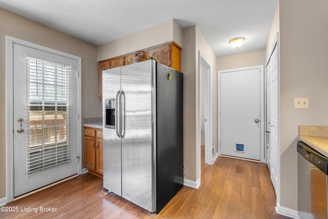 kitchen with appliances with stainless steel finishes and light hardwood / wood-style floors