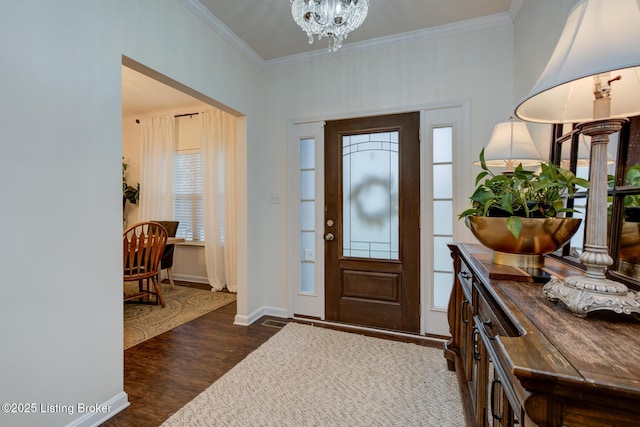 foyer entrance with ornamental molding, dark hardwood / wood-style floors, and a notable chandelier