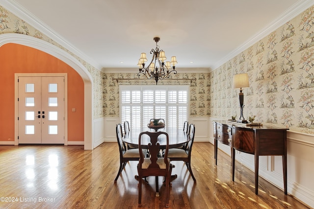 dining room featuring french doors, a notable chandelier, crown molding, and light hardwood / wood-style flooring