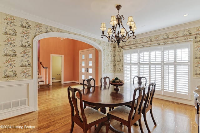 dining room with hardwood / wood-style flooring, a notable chandelier, and crown molding