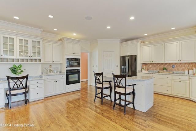 kitchen with light stone counters, light hardwood / wood-style flooring, stainless steel refrigerator with ice dispenser, double oven, and white cabinets