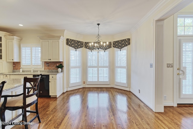 dining room with sink, hardwood / wood-style flooring, a notable chandelier, and ornamental molding