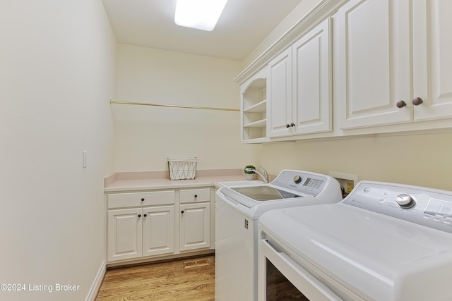 clothes washing area with sink, cabinets, washer and clothes dryer, and light hardwood / wood-style flooring