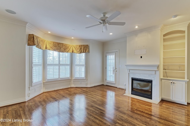 unfurnished living room featuring a premium fireplace, hardwood / wood-style floors, ceiling fan, and ornamental molding