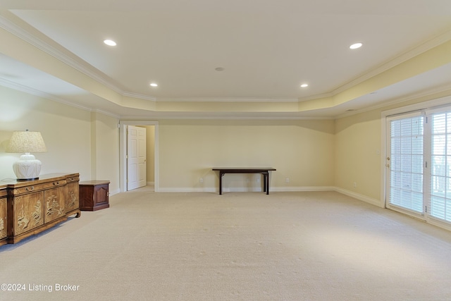 spare room with ornamental molding, light colored carpet, and a tray ceiling